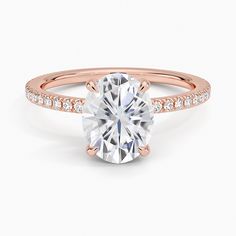 a rose gold engagement ring with an oval cut diamond in the center and pave set shoulders