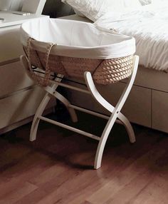 a white bed sitting next to a basket on top of a wooden floor in a bedroom