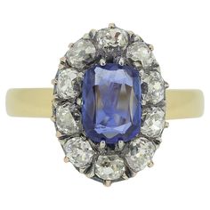 Here we have a stunning sapphire and diamond cluster ring. This antique piece features an single oval shaped cushion cut natural unheated sapphire at the centre of the face possessing a bright cornflower blue colour tone. This principle stone is then framed by a halo of chunky old mine cut diamonds around the outer edge. The mid blue of the sapphire is wonderfully complimented by the white radiance of the diamonds before the piece is made complete by a plain polished 18ct yellow gold band. The head of this ring was expertly converted from a French 19th Century bracelet and crafted onto a more recent band by master antique jewellery restorer and re-designer, Gaetano Chiavetta. Condition: Used (Very Good) Weight: 5.0 grams Size: M (53) Band Width: 2.5mm Face Dimensions: 16mm x 11mm Sapphire