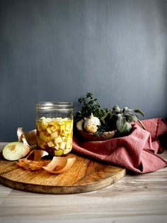 a jar filled with food sitting on top of a wooden cutting board next to an apple