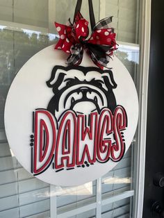 a door hanger with the word dawgs painted on it and a bow