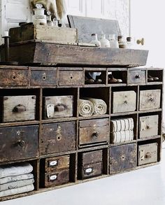 an old wooden dresser with many drawers and items on it's sides, in front of a white wall