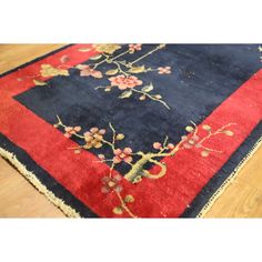 a blue and red area rug with flowers on the border, sitting on a wooden floor