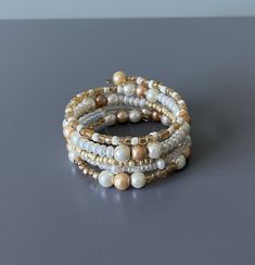 Elegant glass bead memory wire bracelet in shades of gold and white. Beads are multiple sizes with the largest being 8mm. Bracelet measures 7 inches around but expands. Memory wire adjusts to most sizes and gives the appearance of wearing multiple bracelets. This would be beautiful for a wedding or any special occasion. This bracelet is eye catching when being worn! We hope you love our bracelet. We took great pride in making it! If you have any questions, please don't hesitate to message me! If Elegant Pearl Jewelry, Beaded Memory Wire Bracelets, Multiple Bracelets, Bracelet Fil, Bracelet Elegant, Beaded Memory Wire, Memory Wire Bracelet, Memory Wire Bracelets, Beaded Wraps