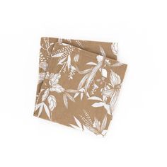 two brown napkins with white flowers and leaves on them, one is folded to the side