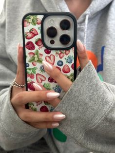 a woman holding up her phone case with strawberries on it