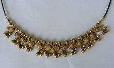 Golden Necklace from Kolhapur, India Gold, filled with wax to prevent denting Early 20th century Size of the golden part: 18cm Length of the full necklace 70 cm The necklace has 13 gold pendants, six of which appear in pairs. On each pendant are three small gold beads Between the pendants different gold beads The goldparts are filled with wax to prevent denting Mounted on a cord with a sliding knot so that it can be worn at different lengths Very decorative with a beautiful patina This is only a Antique 22k Gold Engraved Jewelry, Antique Engraved 22k Gold Jewelry, Vintage 22k Gold Engraved Jewelry, Gold Pendant Necklace For Rituals, Vintage 22k Gold Jewelry For Festive Occasions, Vintage Necklace With Latkans For Gift, Antique Locket Jewelry For Festivals, Ornate Ceremonial Hallmarked Necklace, Gold Temple Jewelry Necklaces With Latkans