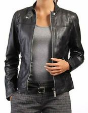 a woman wearing a black leather jacket and grey shirt is holding her stomach in front of the camera