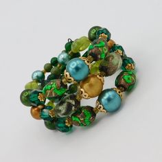 Pretty artisan made wire cuff bracelet easily fits a a 7-8 inch wrist.  Made with beautiful selection of irredescent green art glass beads, faceted green glass beads, satin finished beads and round glass beads about to finish out the ends.  Large beads of gold tone filigree bead caps.  The color combination is wonderful with bright green foil glass and varying shades of green and gold satin finished beads.  Bracelet is 1 1/4 inch wide and in very good vintage condition. Green Bohemian Stretch Bracelet With Faceted Beads, Green Bohemian Wrap Bracelet With Round Beads, Green Stretch Bracelet With Faceted Round Beads, Green Bohemian Stretch Bracelet With Large Beads, Green Glass Round Bead Jewelry, Green Beaded Glass Jewelry, Green Wire Wrapped Jewelry For Party, Green Glass Beaded Jewelry, Elegant Green Hand Wrapped Bracelets