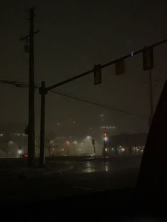 the traffic lights are hanging over the street at night in the foggy cityscape