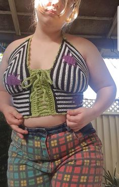 a woman wearing plaid pants and a halter top standing in front of a house