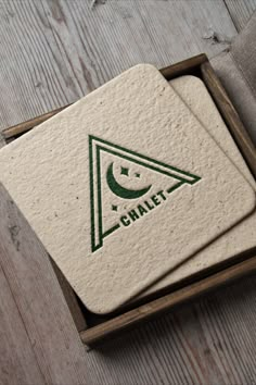 two coasters sitting in a box on top of a wooden table with the word chalet printed on them