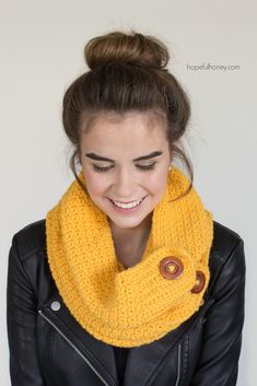 a woman wearing a yellow knitted cowl with a wooden button on it's side