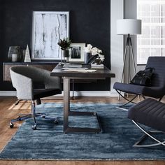 a living room with a chair, desk and rug on the floor in front of a window