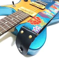 a guitar strap with flowers on it sitting on top of a blue electric guitar case