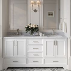 a white bathroom with marble counter tops and double sinks