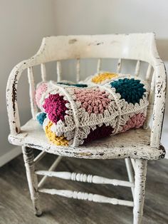 a crocheted pillow sitting on top of an old white chair in a room