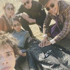 a group of people sitting next to each other on top of a dirt field together