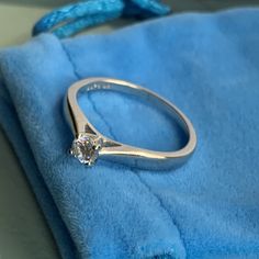 a diamond ring sitting on top of a blue velvet bag