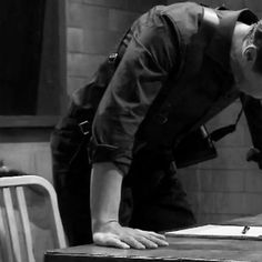 black and white photograph of a man leaning over a table