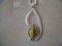 A unique 10x14mm cabochon of Tiger's eye hand bezel set in fine silver. The traditional setting is hand forged Argentium sterling silver, that suspends and frames the stone. All surfaces are hand polished to a mirror finish, no excess solder anywhere. A fine handcrafted piece that is stamped Sterling, and Hallmarked on the back. Comes with a 18" chain. Overall height 2" width 7/8" Handmade Sterling Silver Teardrop Gemstones, Handmade Teardrop Sterling Silver Gemstones, Artisan Oval Jewelry With Bezel Setting, Artisan Sterling Silver Jewelry With Polished Finish, Spiritual Jewelry With Oval Pendant And Polished Finish, Teardrop Silver Gemstones For Jewelry Making, Spiritual Sterling Silver Jewelry With Bezel Setting, Teardrop Cabochon Jewelry For Anniversary, Anniversary Teardrop Cabochon Jewelry