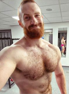 a man with no shirt standing in a gym