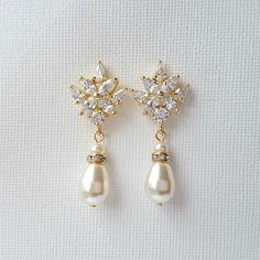 a pair of earrings with pearls and diamonds on them, sitting on a white surface