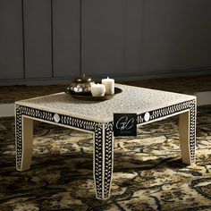 a coffee table with candles on it in front of a rug