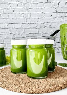 three jars filled with green liquid sitting on top of a cork coaster