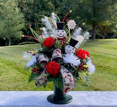 a vase filled with red and white flowers sitting on top of a cement slab in the grass