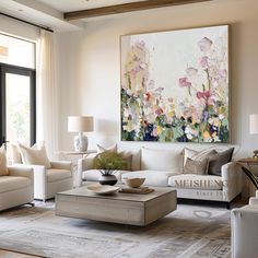 a living room filled with furniture and a large painting on the wall above it's windows