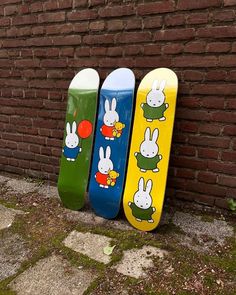 three skateboards are lined up against a brick wall, with bunnies on them