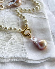 This hand-knotted pearl shell necklace features a charming baroque pearl charm, perfect for adding some whimsy to your wardrobe. At 16 inches in length, it's a versatile piece that can be dressed up or down for any occasion. Embrace your playful side with Geniva Pearls! Pearl White Necklace With Pearl Charm, Baroque Pearl Bracelet With Pendant For Wedding, Wedding Pearl Bracelet With Baroque Pendant, Wedding Pearl Bracelet With Baroque Pearl Pendant, Gift Pearl Necklace With Lobster Clasp, Pearl White Necklace With Lobster Clasp As Gift, Pearl White Pearl Necklace With Charm, Baroque Pearl Necklace With Lobster Clasp As Gift, Pearl Pendant Necklace With Lobster Clasp