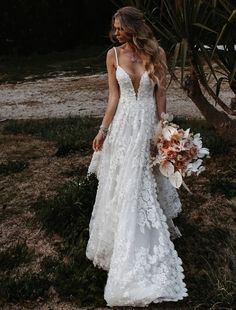 a woman in a wedding dress holding a bouquet and looking at the camera with her back to the camera