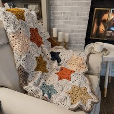 a crocheted blanket is sitting on a chair in front of a fire place