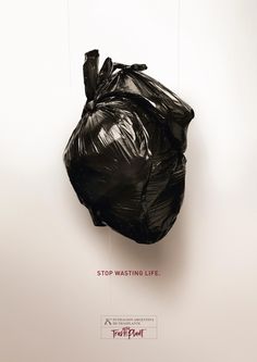 a black plastic bag hanging on a wall with the words stop wasteing life above it