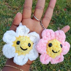 two small crocheted flowers are held in the palm of someone's hand