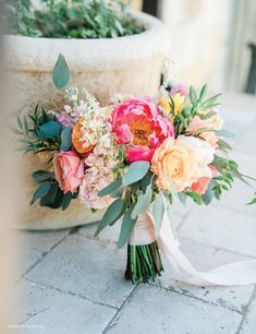 a bridal bouquet sitting on the ground in front of a potted planter