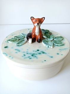 a small ceramic fox sitting on top of a white box