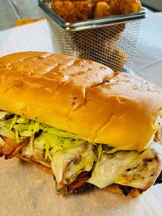 a large sandwich sitting on top of a cutting board next to some fried chicken wings