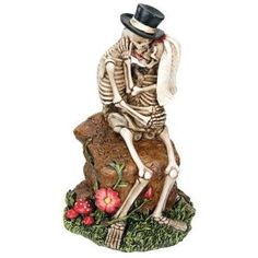 a skeleton sitting on top of a rock with a flower in it's hand