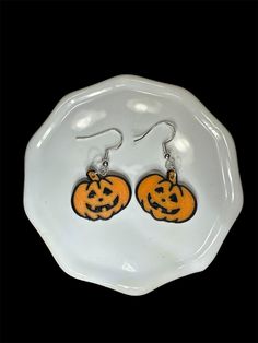 two pumpkins with faces on them are hanging from earrings