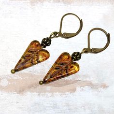 Glass heart earrings in golden honey topaz with Picasso finish are the perfect Bohemian handmade jewelry gift. Their rich colors evoke a sense of woodland and nature. These Czech glass earrings look great with a variety of styles, from casual to dressy. Add them to your earring collection while they last! Custom ear wire style choice at checkout. Hypoallergenic ear wires (nickel and lead free).  Free gift packaging included. Earrings are carded and in an organza bag. Artisan glass beads produced Elegant Cheap Czech Glass Earrings, Unique Heart Drop Earrings As Gift, Nickel-free Unique Heart Earrings, Unique Nickel-free Heart-shaped Earrings, Yellow Brass Earrings As A Gift, Dangle Heart Earrings As Gift, Brown Czech Glass Jewelry Gift, Elegant Yellow Heart Earrings, Yellow Heart Beads Jewelry For Gift