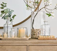 vases with flowers and candles sit on a dresser