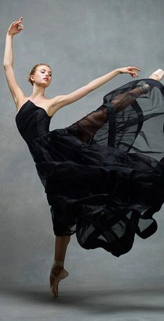 a woman in a black dress is dancing