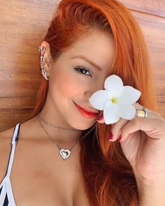 a woman with red hair holding a white flower