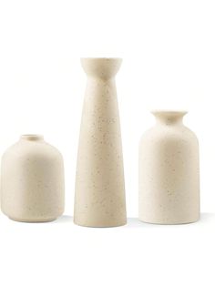 three white vases sitting next to each other on a white surface with tiny speckles