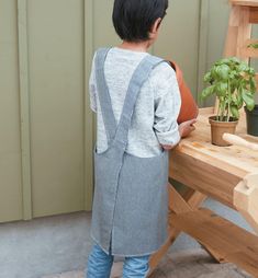 a little boy standing next to a wooden bench with a potted plant on it