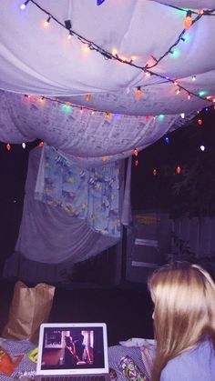 a laptop computer sitting on top of a table under a canopy covered in string lights