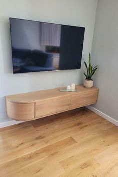 a flat screen tv mounted on the wall above a wooden table with two planters